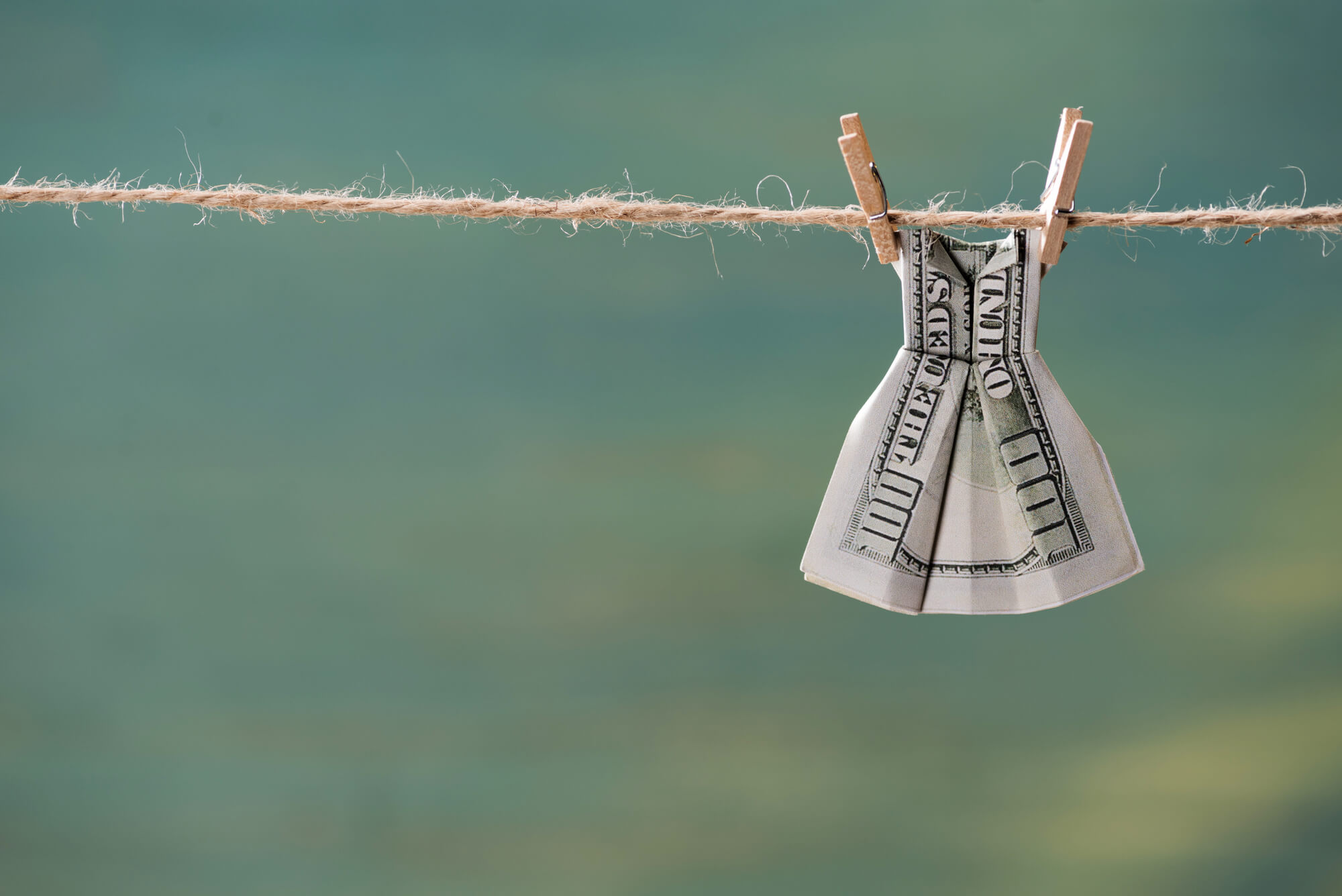 dollar bill folded into shape of dress and hanging on clothesline