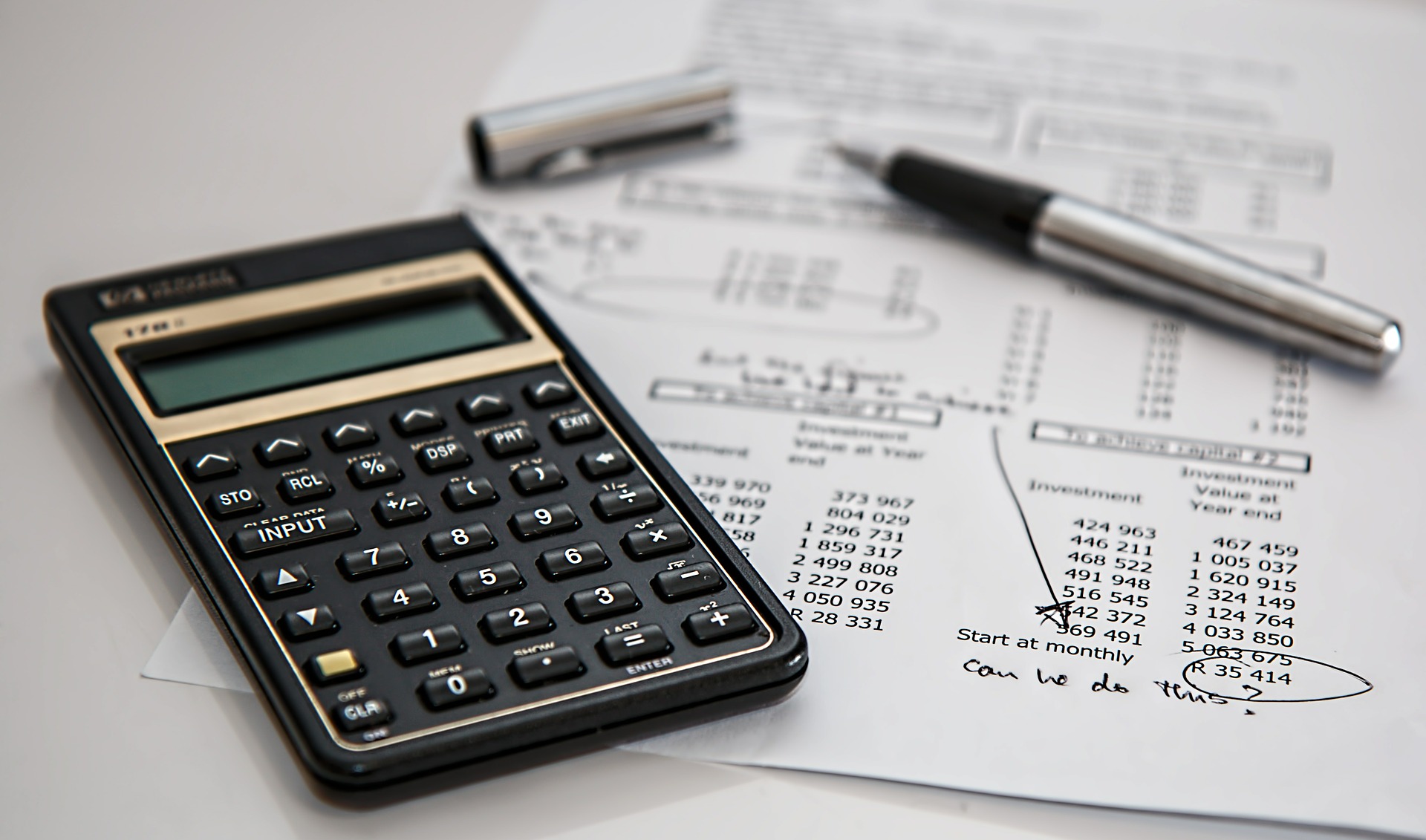 a black calculator, pen, and budget sheet