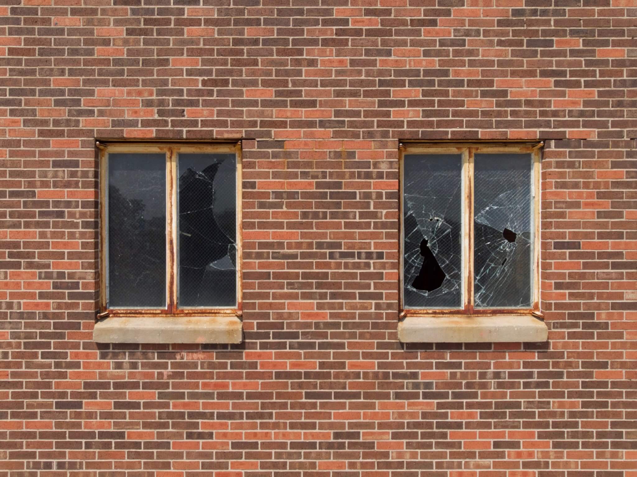 two broken windows in brick wall